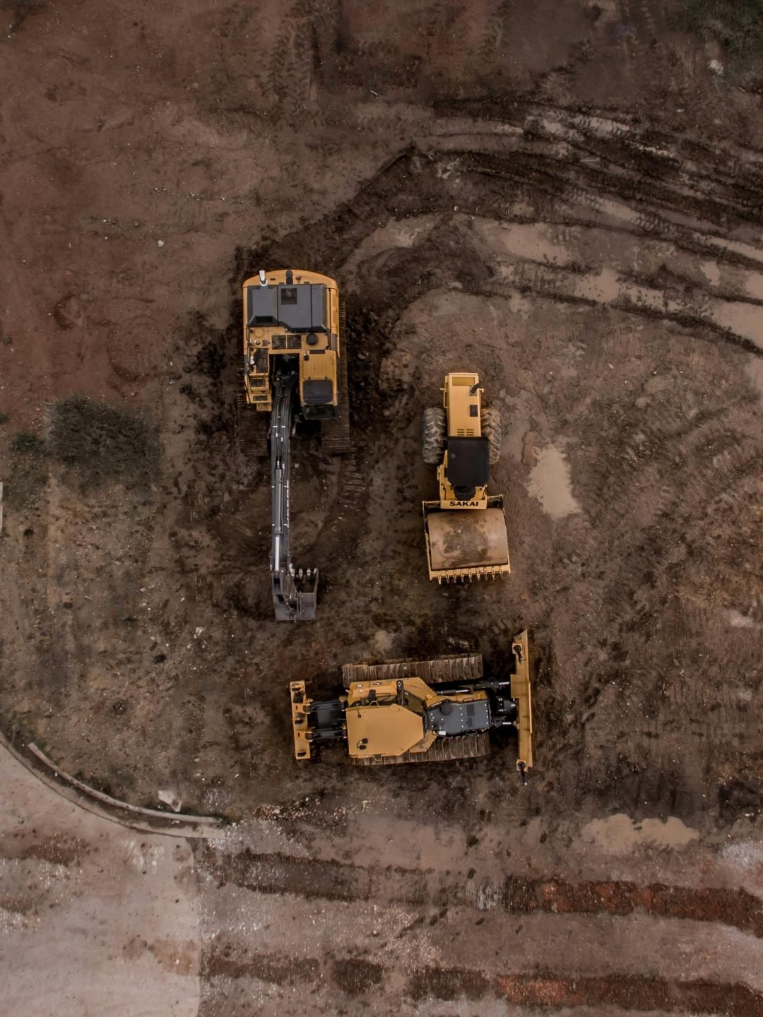 An aerial shot of heavy machinery at a construction site, including excavators and road rollers.
