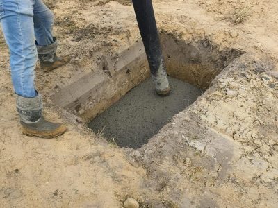 Worker using hose to pour concrete into foundation at site in Poland.