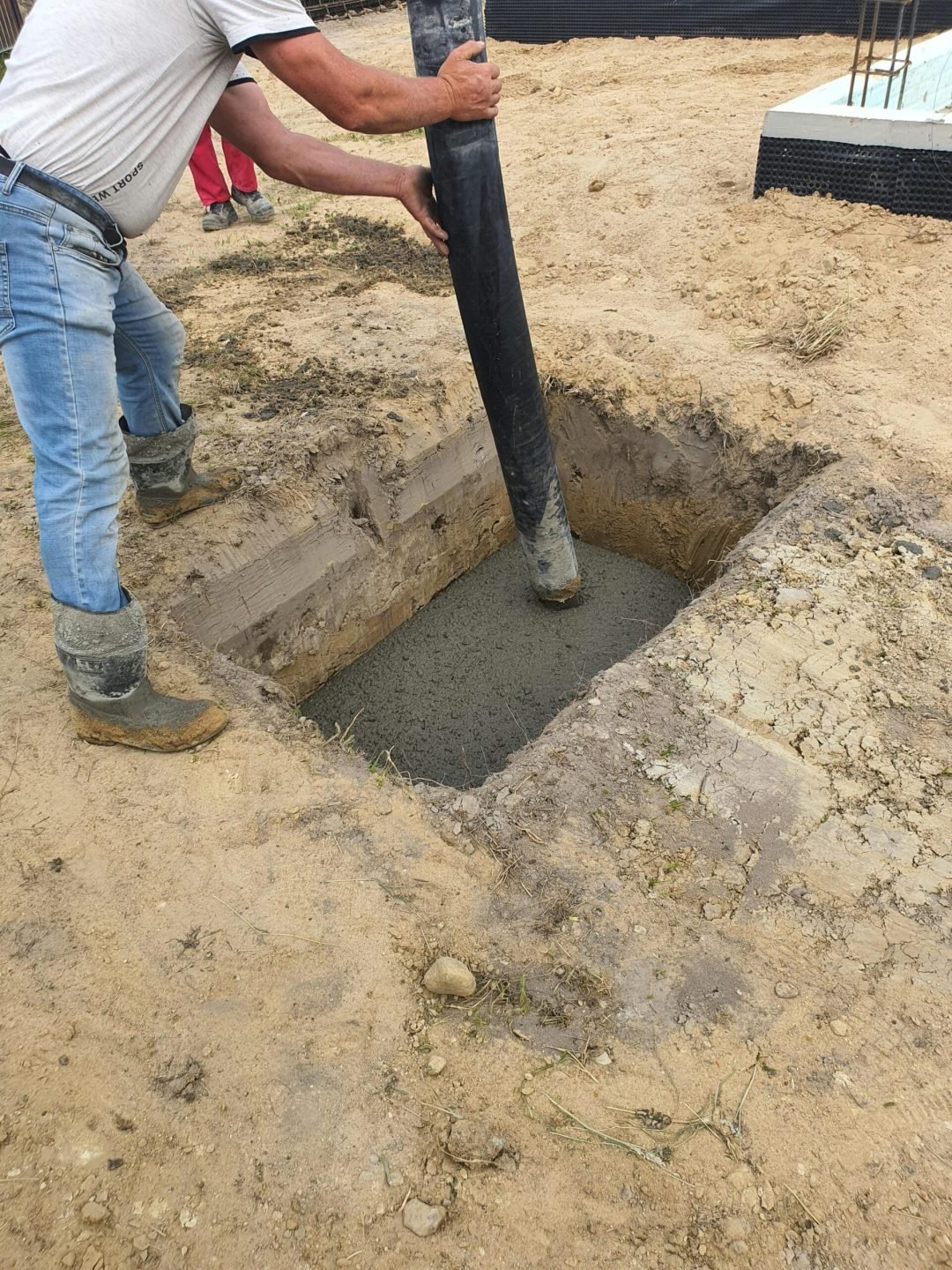 Worker using hose to pour concrete into foundation at site in Poland.