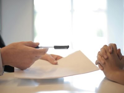 Close-up of a contract signing with hands over documents. Professional business interaction.
