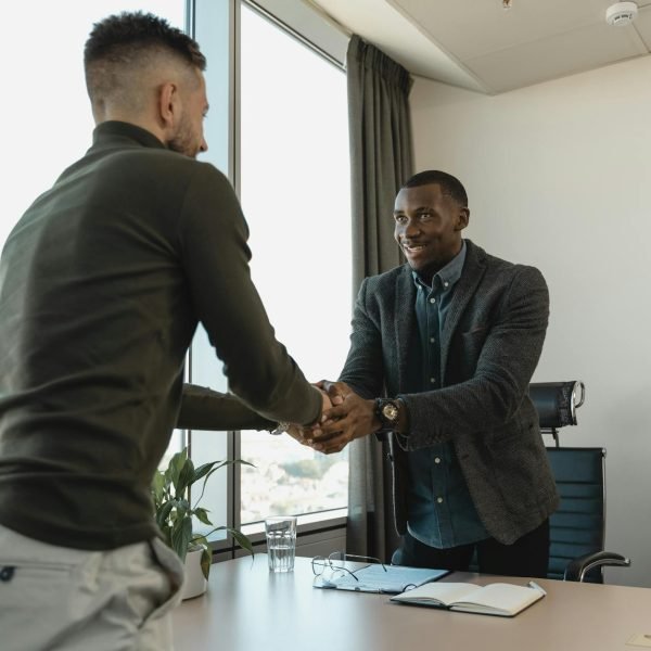 Two businessmen exchanging a handshake during a professional meeting in a modern office setting.