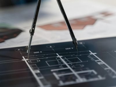 A compass on architectural blueprints, showcasing planning and measurement details.