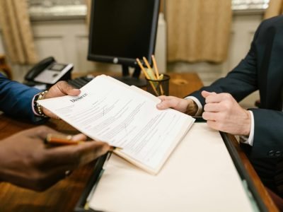 Close-up of hands exchanging divorce documents during legal proceedings in office.